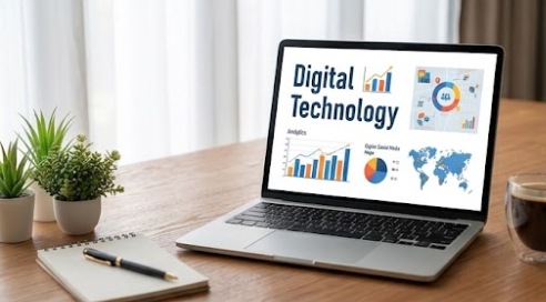 Laptop on a desk displaying the words Digital Technology, with colorful marketing graphics and a small plant beside it